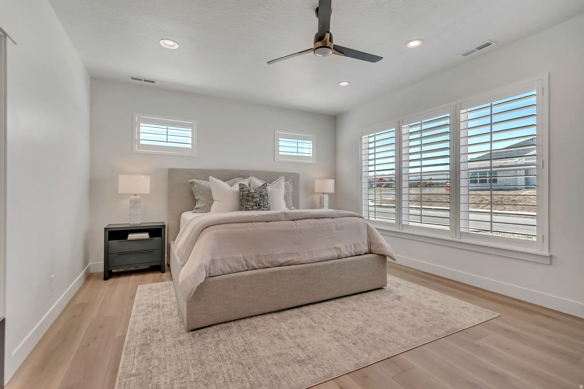 Recessed lighting, ceiling fan, wood-finish flooring, and white plantation shutters on multiple windows