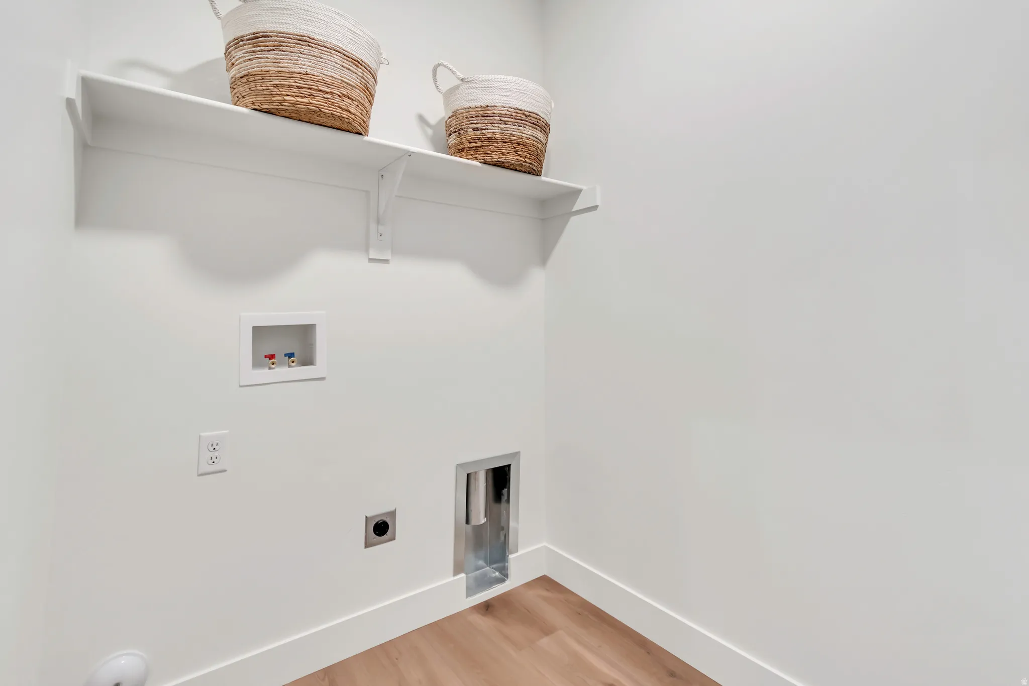 White wall-mounted shelving, wood-finish flooring, and white wall trim