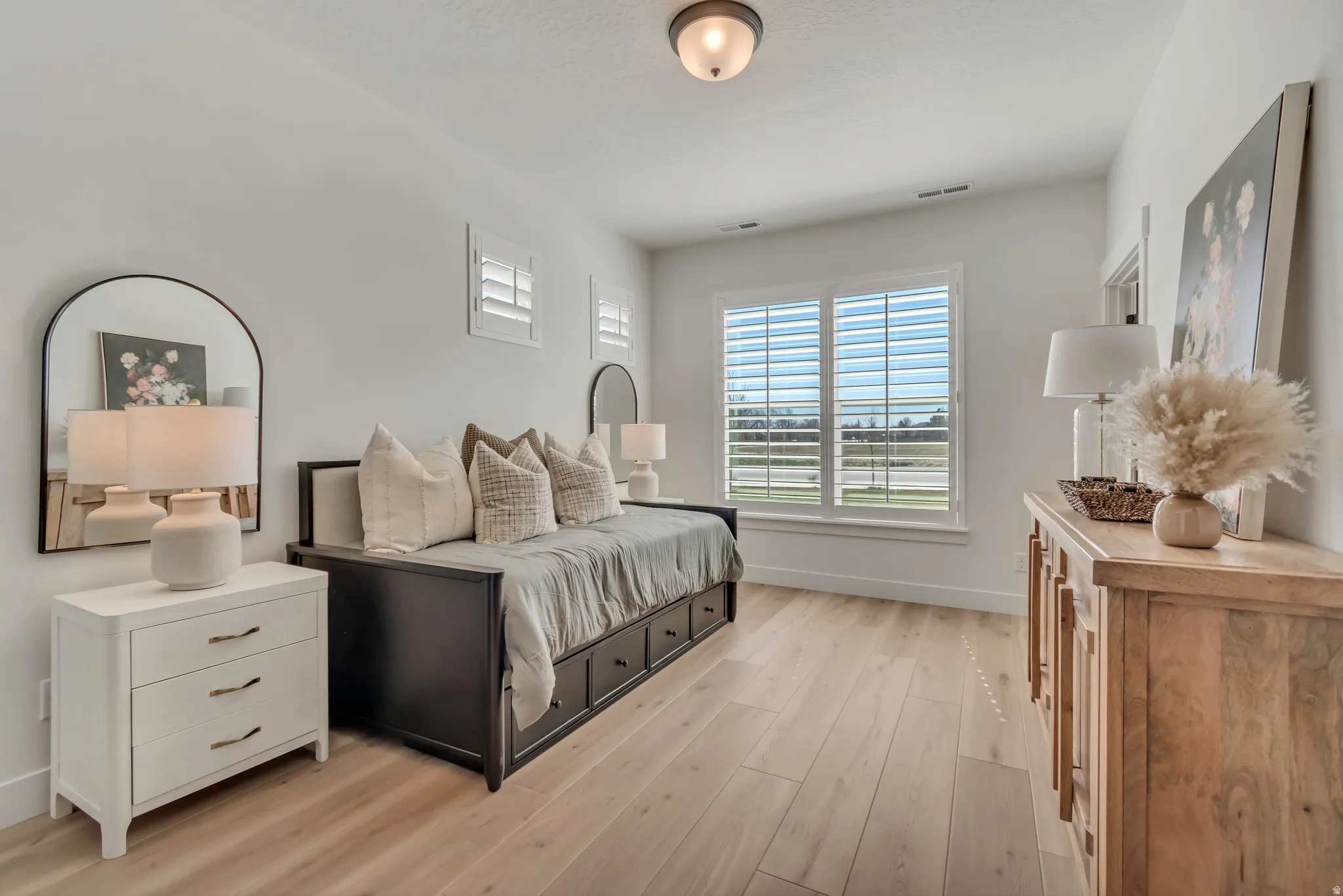 Light wood-finish flooring, white walls, and a multi-pane window with white plantation shutters