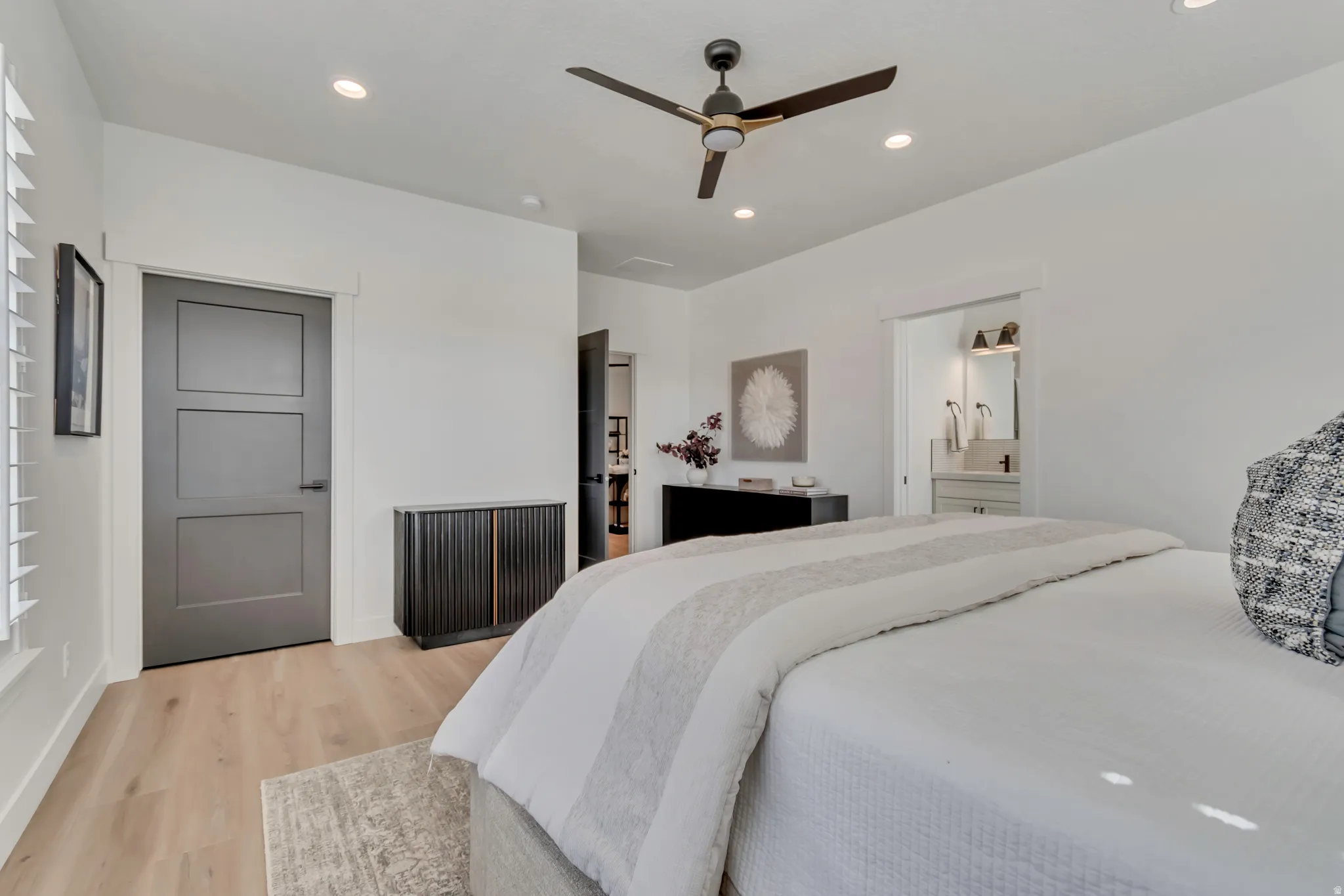 Light wood-finish flooring, modern ceiling fan, recessed lighting, and a three-panel interior door