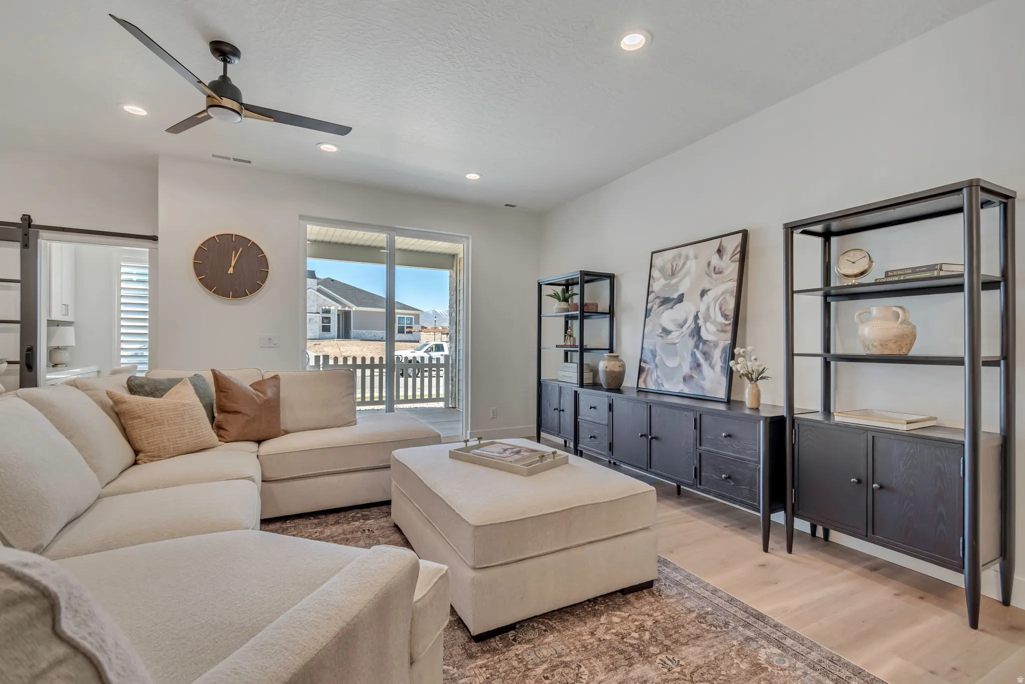 Expansive living area featuring light wood-finish flooring, recessed lighting, and a modern ceiling fan