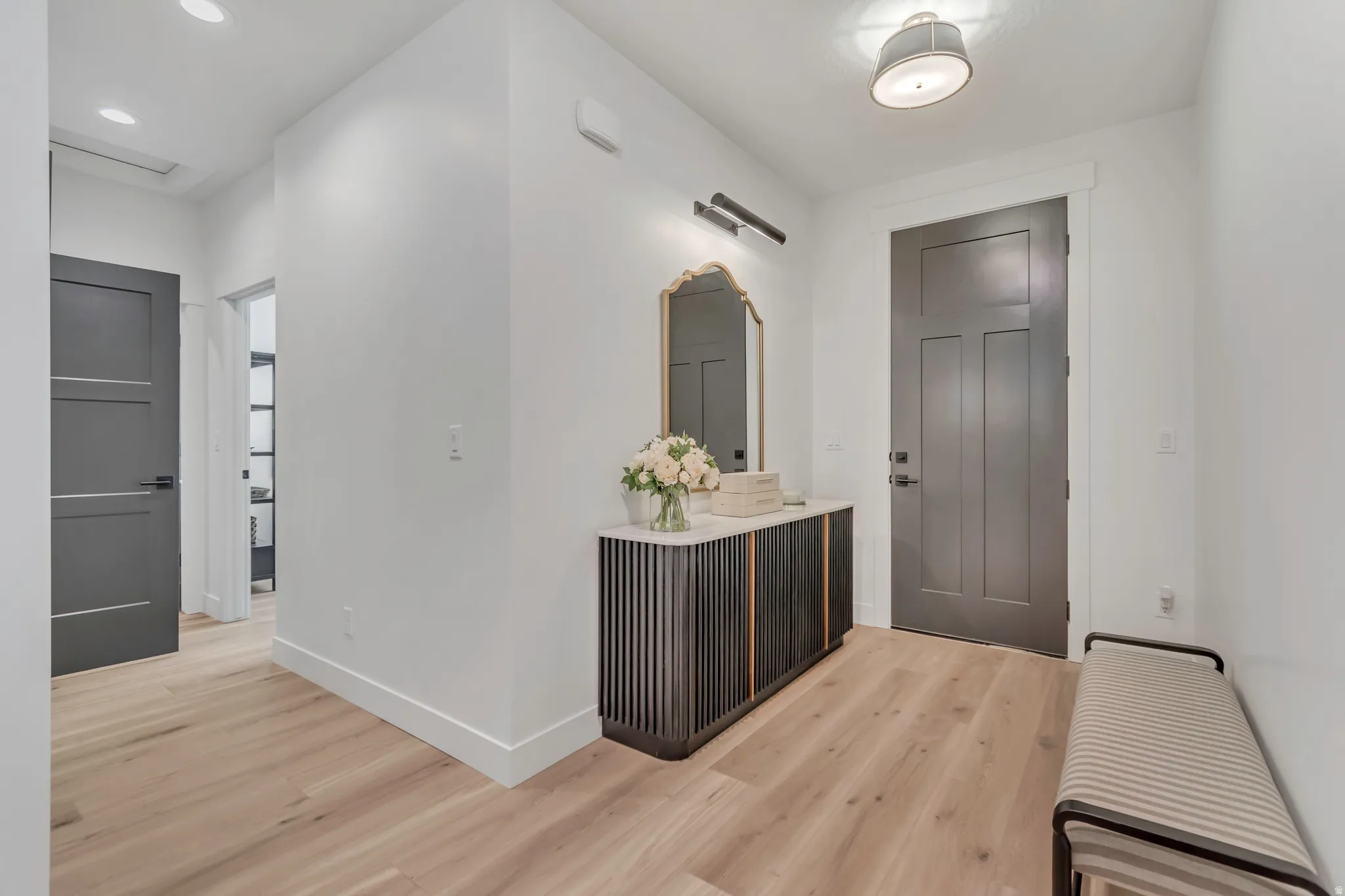 Light wood-finish flooring with recessed lighting and a contemporary ceiling fixture