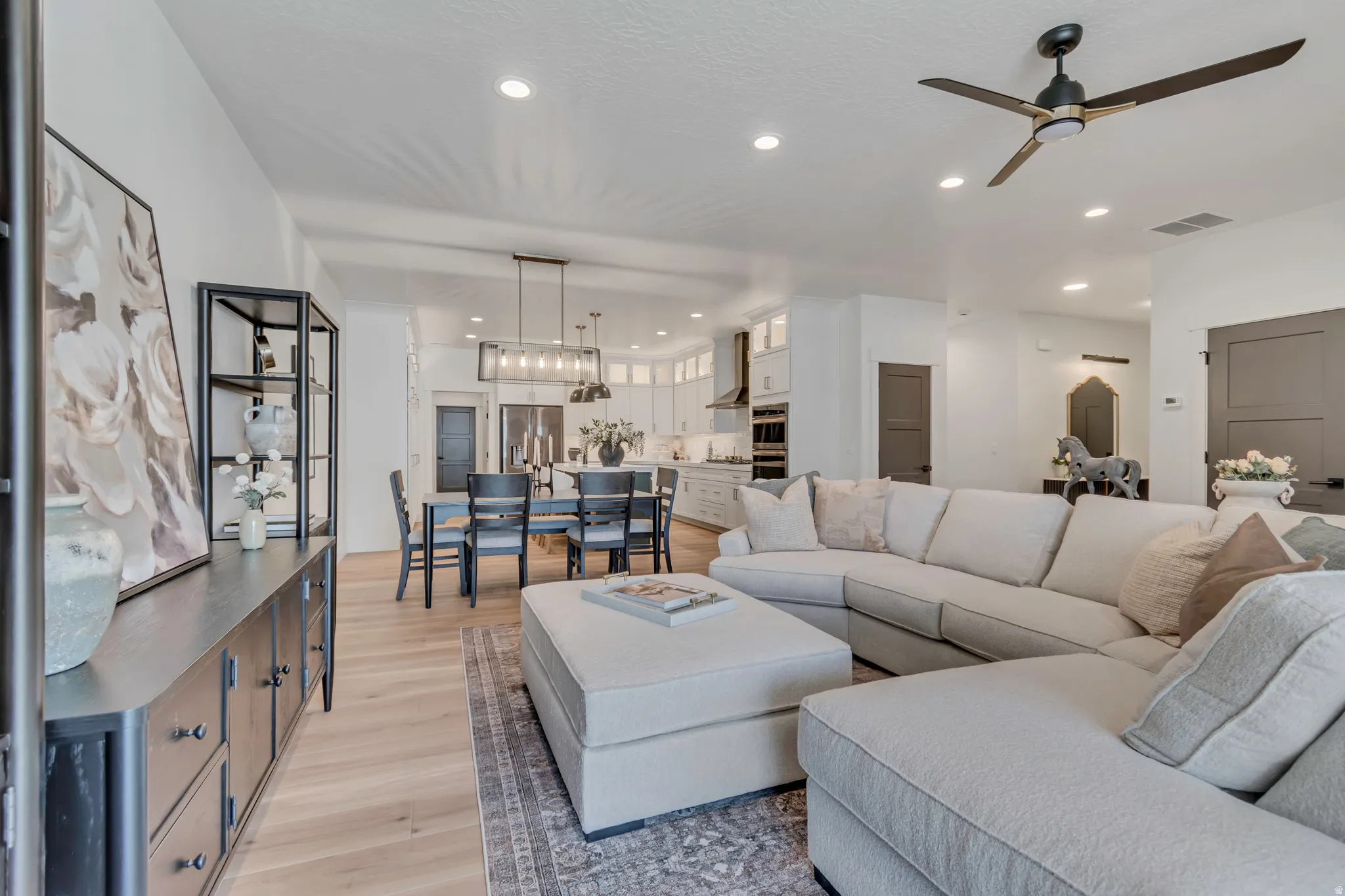 Open-concept living space with light wood-finish flooring, recessed lighting, and a contemporary ceiling fan