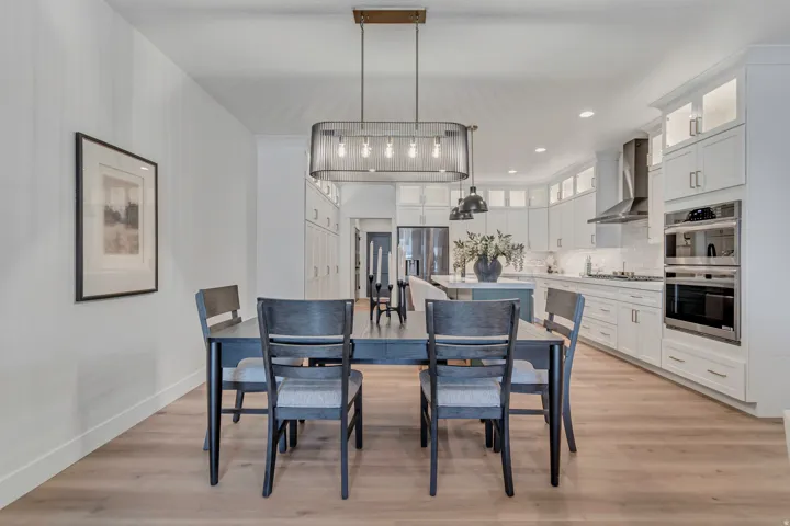 Wood-finish flooring throughout, kitchen with white cabinetry, stainless steel double oven, and stainless steel range hood