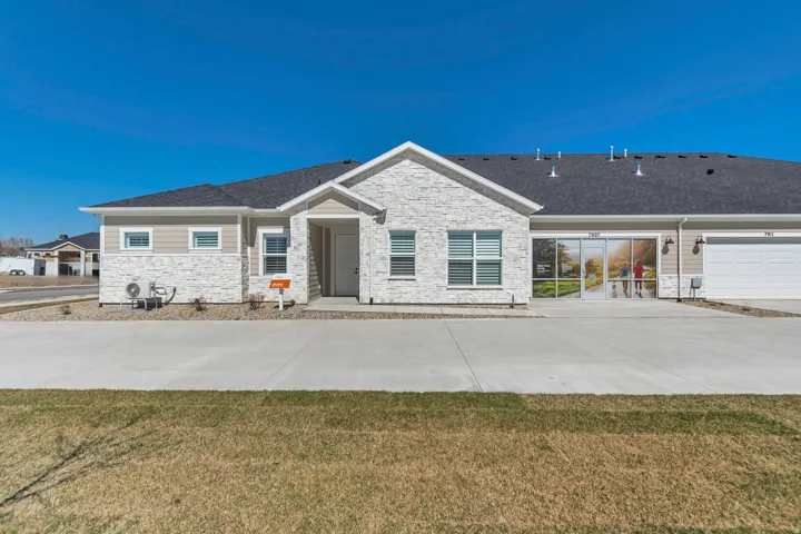 Exterior featuring a stone facade, horizontal siding, attached garage, and a concrete driveway