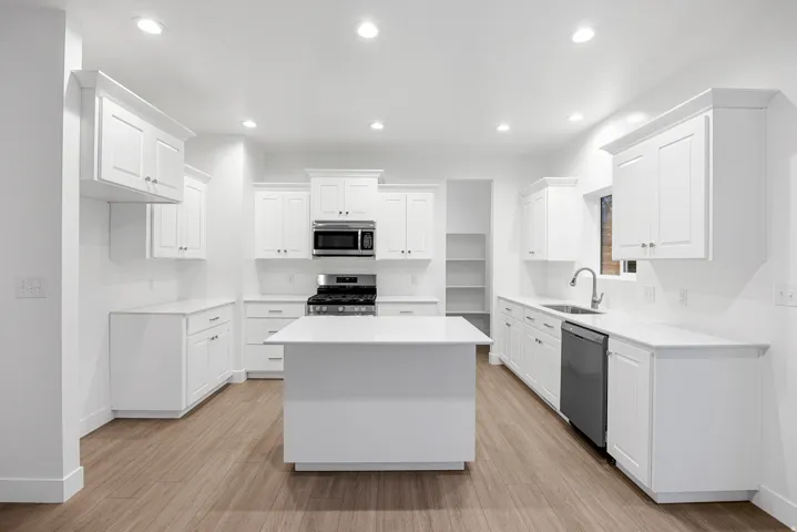 Kitchen featuring white shaker cabinetry, an island, stainless steel appliances, recessed lighting, and wood-finish flooring
