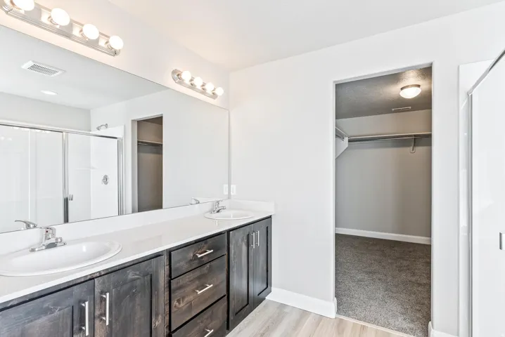 Double vanity with white oval sinks, chrome faucets, and dark wood-finish cabinetry