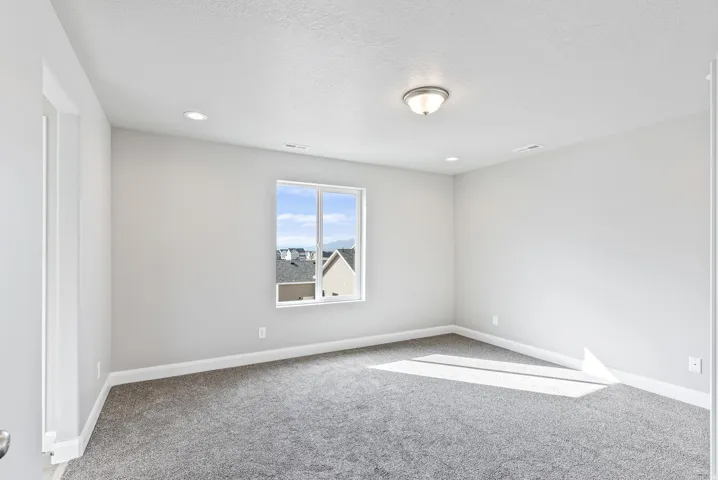 Neutral wall color, recessed lighting, ceiling-mounted light fixture, window with white trim, gray carpeting