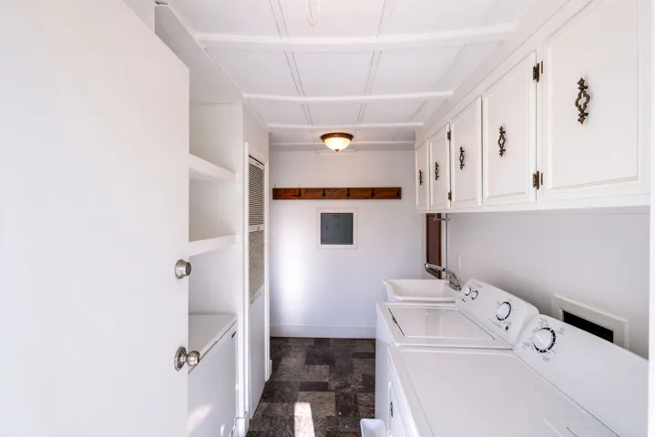 Laundry area featuring upper cabinetry with decorative hardware, a utility sink, and built-in shelving