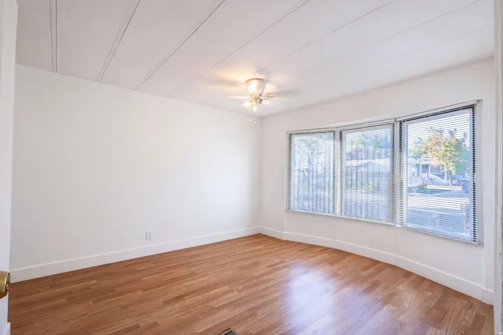 Wood-finish flooring, white walls, and a multi-pane window with blinds