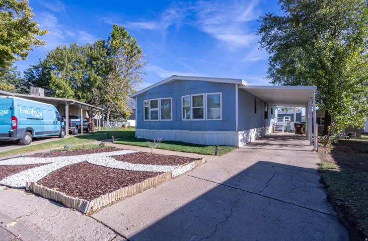 Exterior featuring a light blue siding, white window trim, and a covered carport