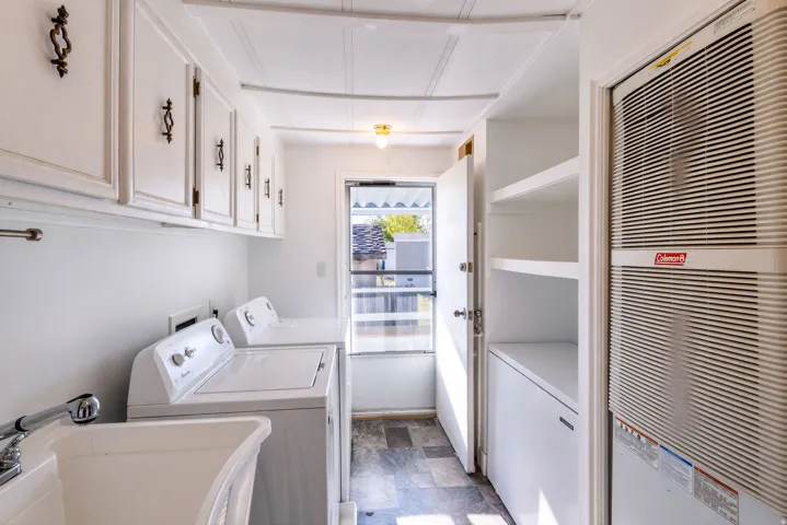 Upper cabinetry with decorative hardware, utility sink with faucet, built-in shelving, and patterned flooring