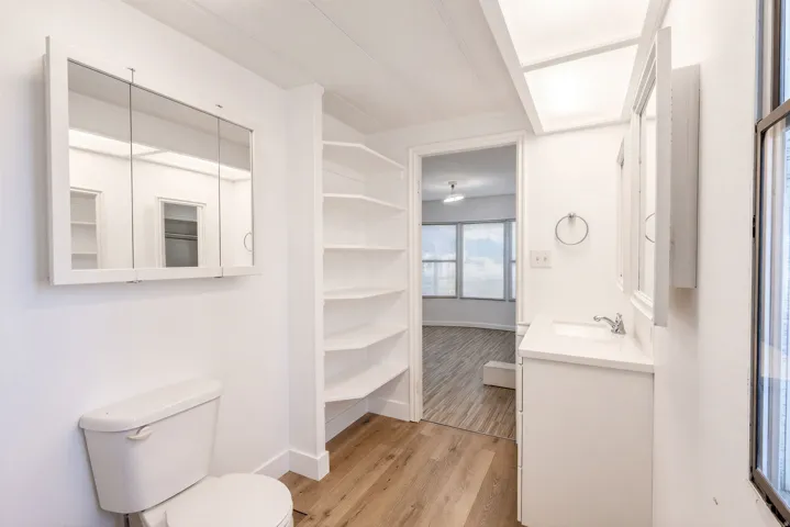 White vanity with integrated sink, chrome faucet, and mirrored medicine cabinet