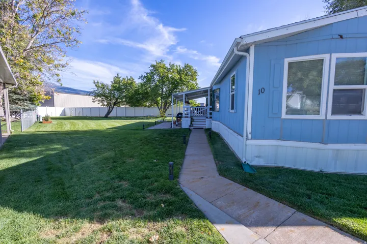 Expansive green lawn, concrete pathway, light blue siding, white trim, and a covered porch