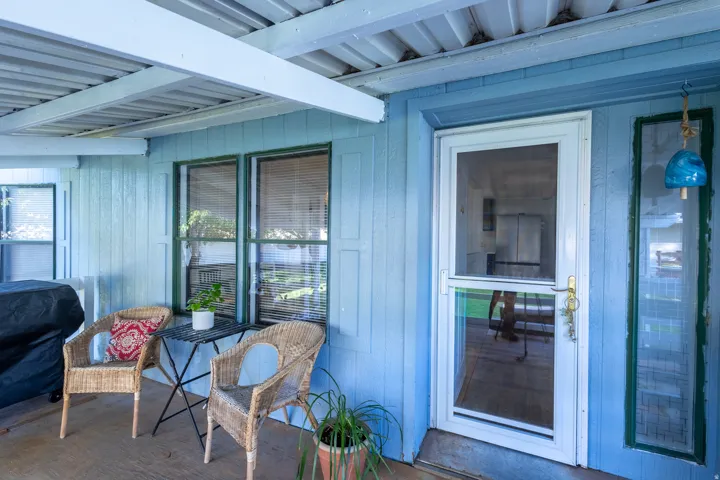 Covered outdoor patio with a screened storm door, vertical wood siding, and multiple windows