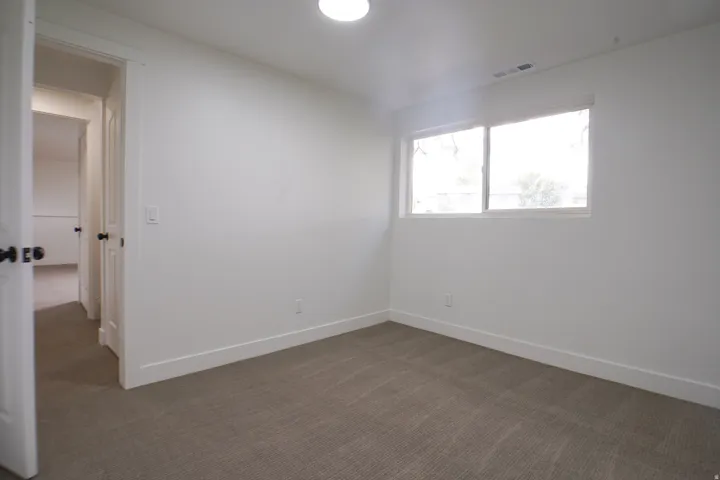 Carpeted room with white walls, a single window, and a flush-mount ceiling light