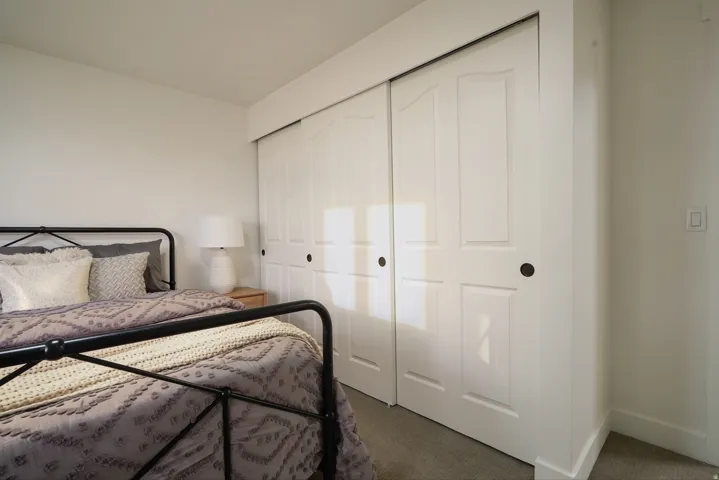 Sliding closet doors with black hardware, light-colored walls, and gray carpeting