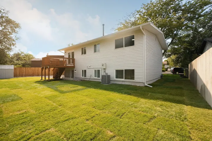 Expansive yard featuring a wood privacy fence, a wooden deck, and a storage shed