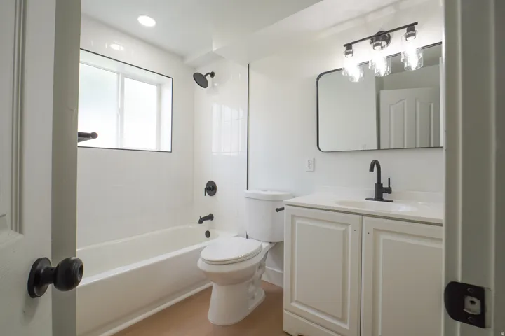 Bathroom featuring a white vanity with paneling, rectangular mirror, and matte black fixtures