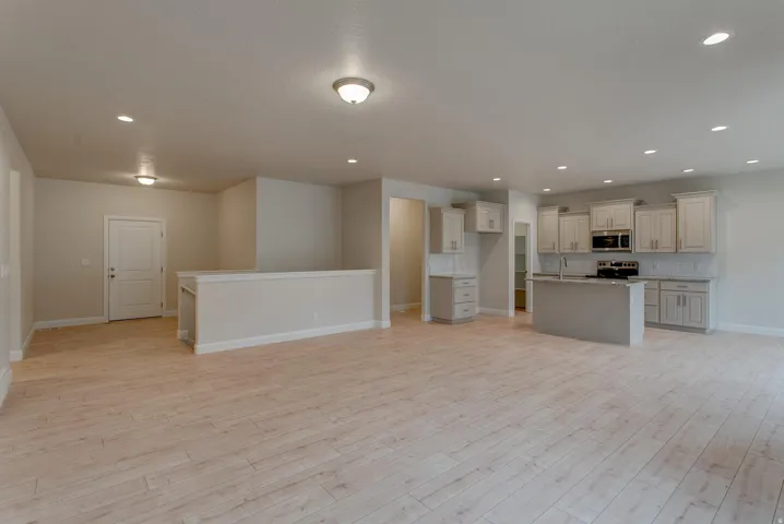 Recessed ceiling lighting, wood-finish flooring, kitchen island, light-toned cabinetry, and stainless steel appliances