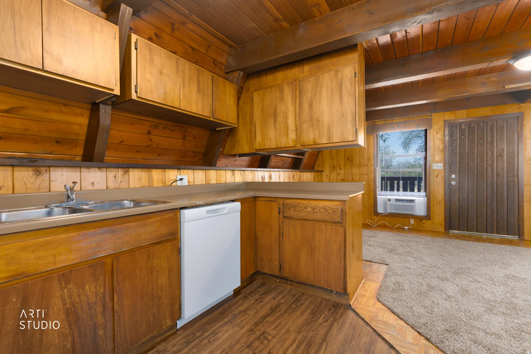Wood-paneled walls and ceiling with exposed beams, wood-finish flooring, built-in cabinetry, and a double basin sink