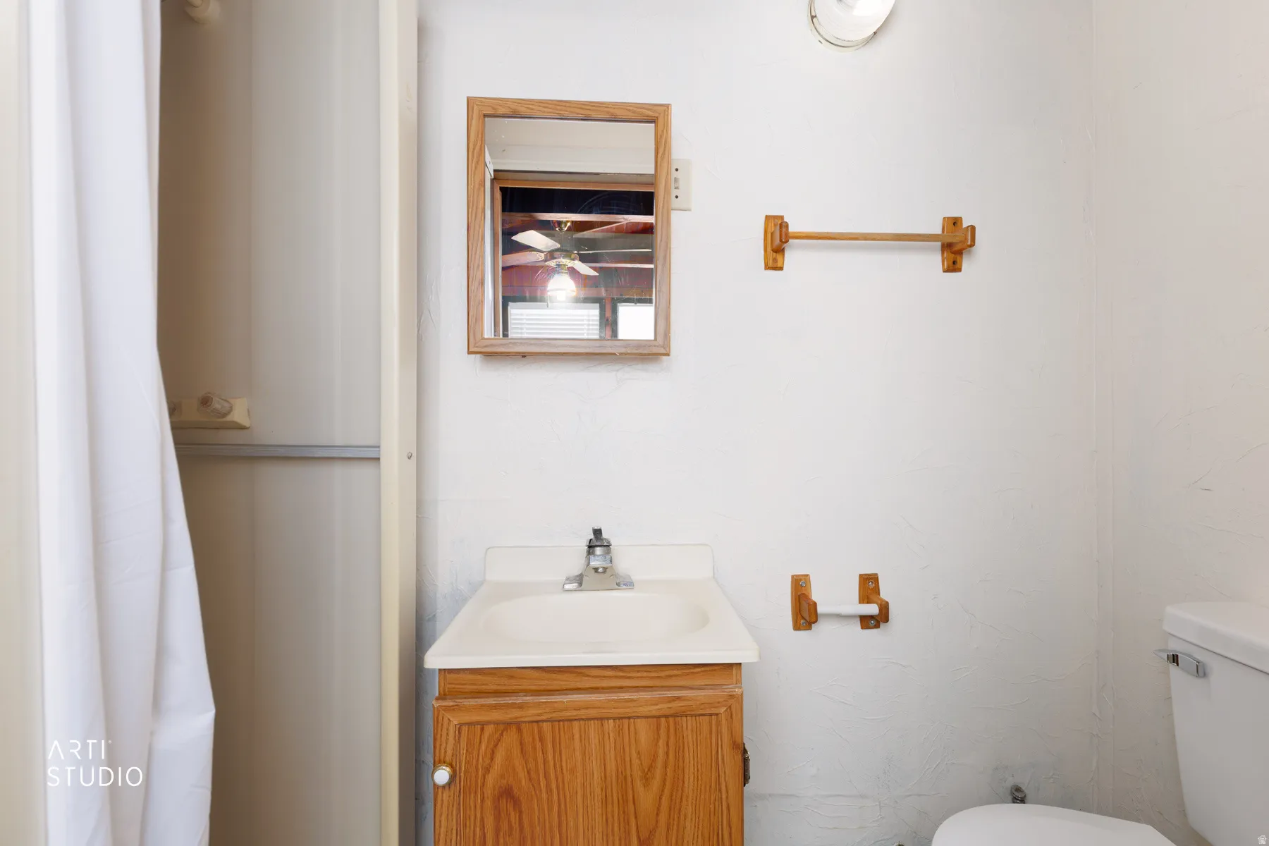 White vanity with integrated sink, wood-finish cabinet, and framed mirror