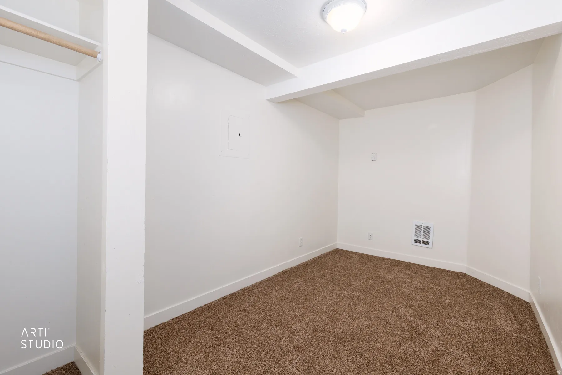 Neutral wall color, overhead lighting, brown carpeting, built-in closet with wooden rod