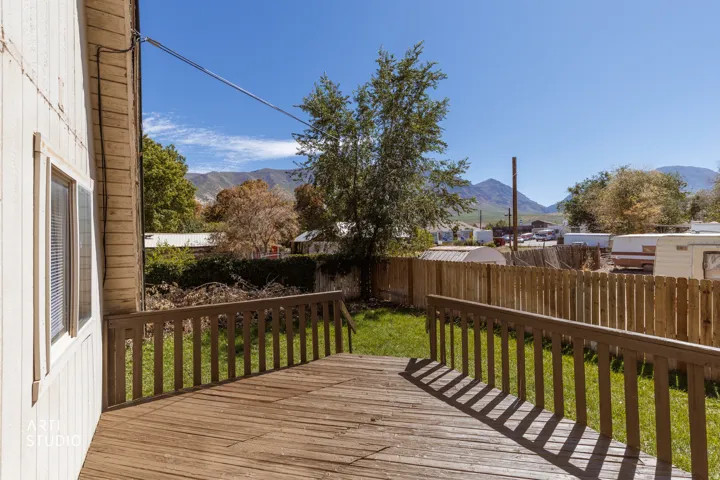 Expansive wooden deck with railing, leading to a grass yard with a wooden fence