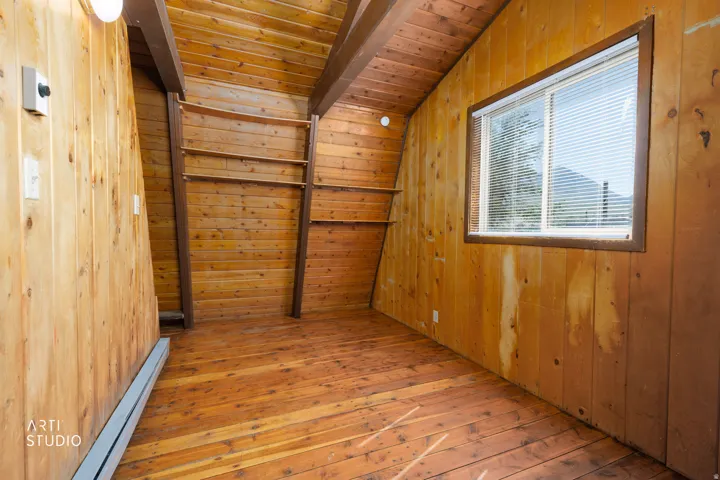 Wood-paneled walls and ceiling, wood-finish flooring, built-in shelving, window with blinds, and exposed beams