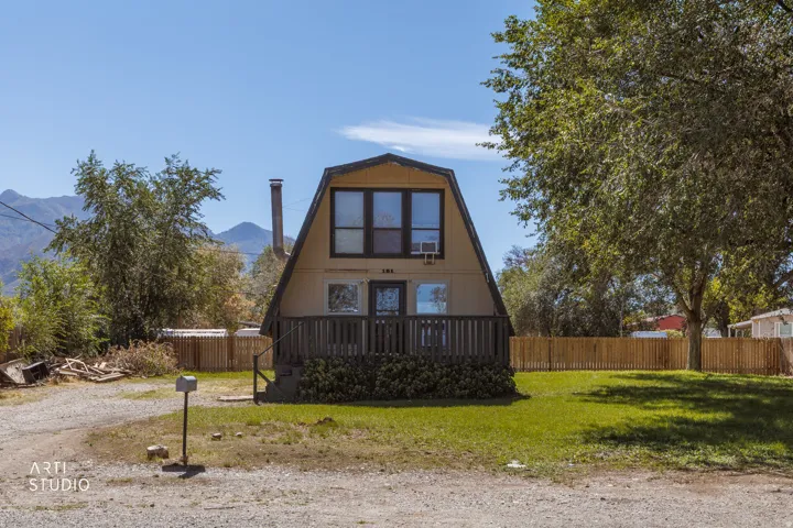 A-frame exterior with a front deck, gravel driveway, and a partially fenced yard