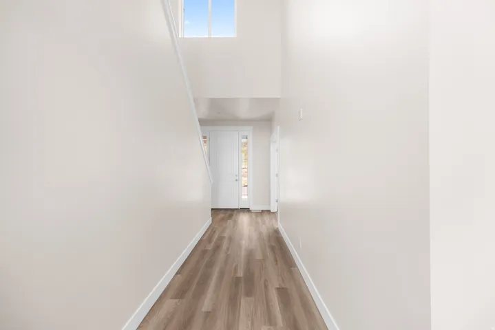 Two-story foyer with wood-finish flooring, white walls, and an overhead window