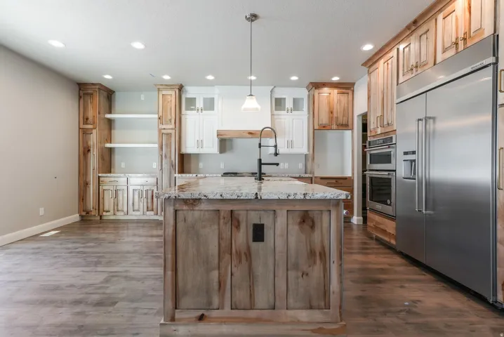 Kitchen featuring a large island with stone countertop, stainless steel appliances, recessed lighting, and wood-finish flooring