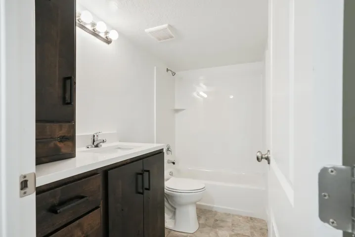 Bathroom featuring a single vanity with dark wood-finish cabinetry, white countertop, and integrated sink