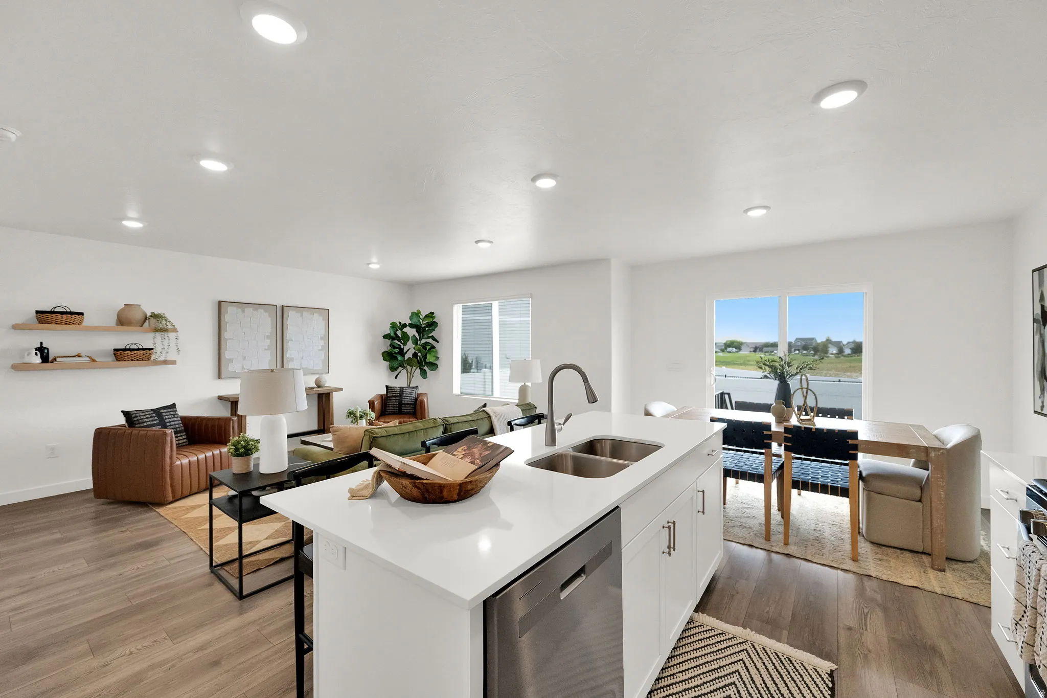 Open-concept living space featuring wood-finish flooring, recessed lighting, and a kitchen island with a stainless steel sink