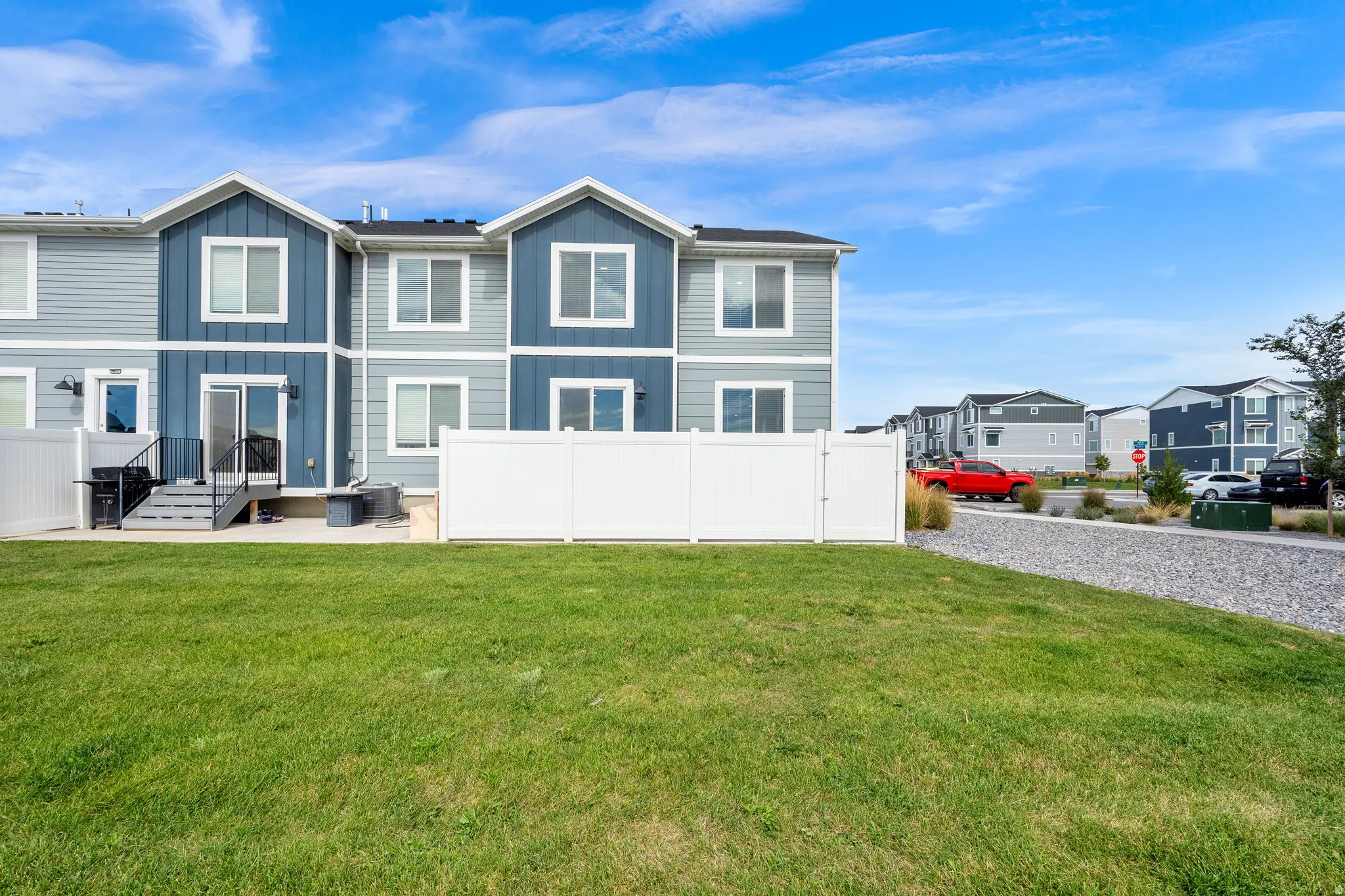 Rear exterior featuring a patio with steps, sliding glass door access, white privacy fencing, and an expansive grassy area