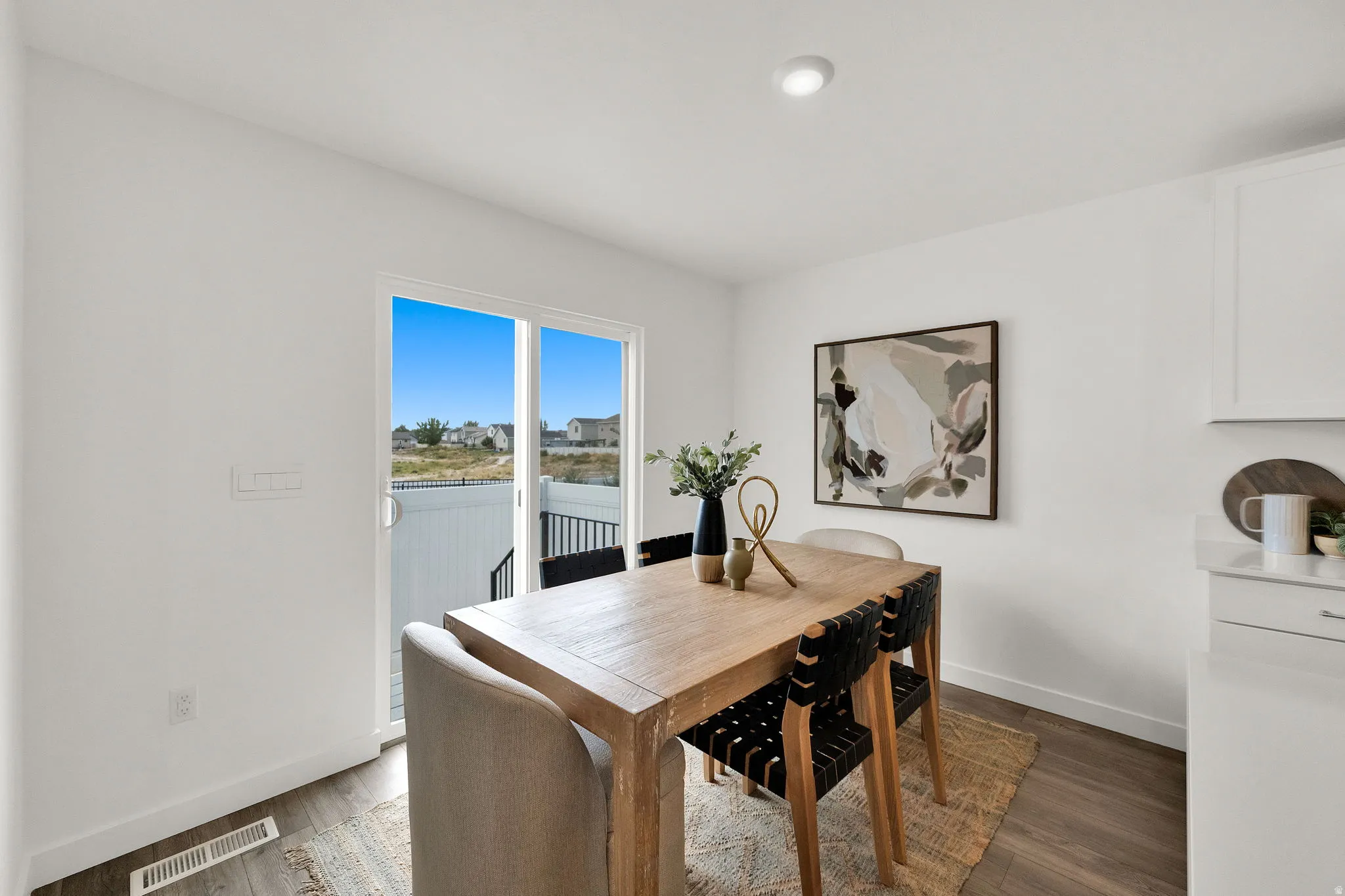 Sliding glass door to an exterior space, recessed ceiling lighting, wood-finish flooring, and white cabinetry