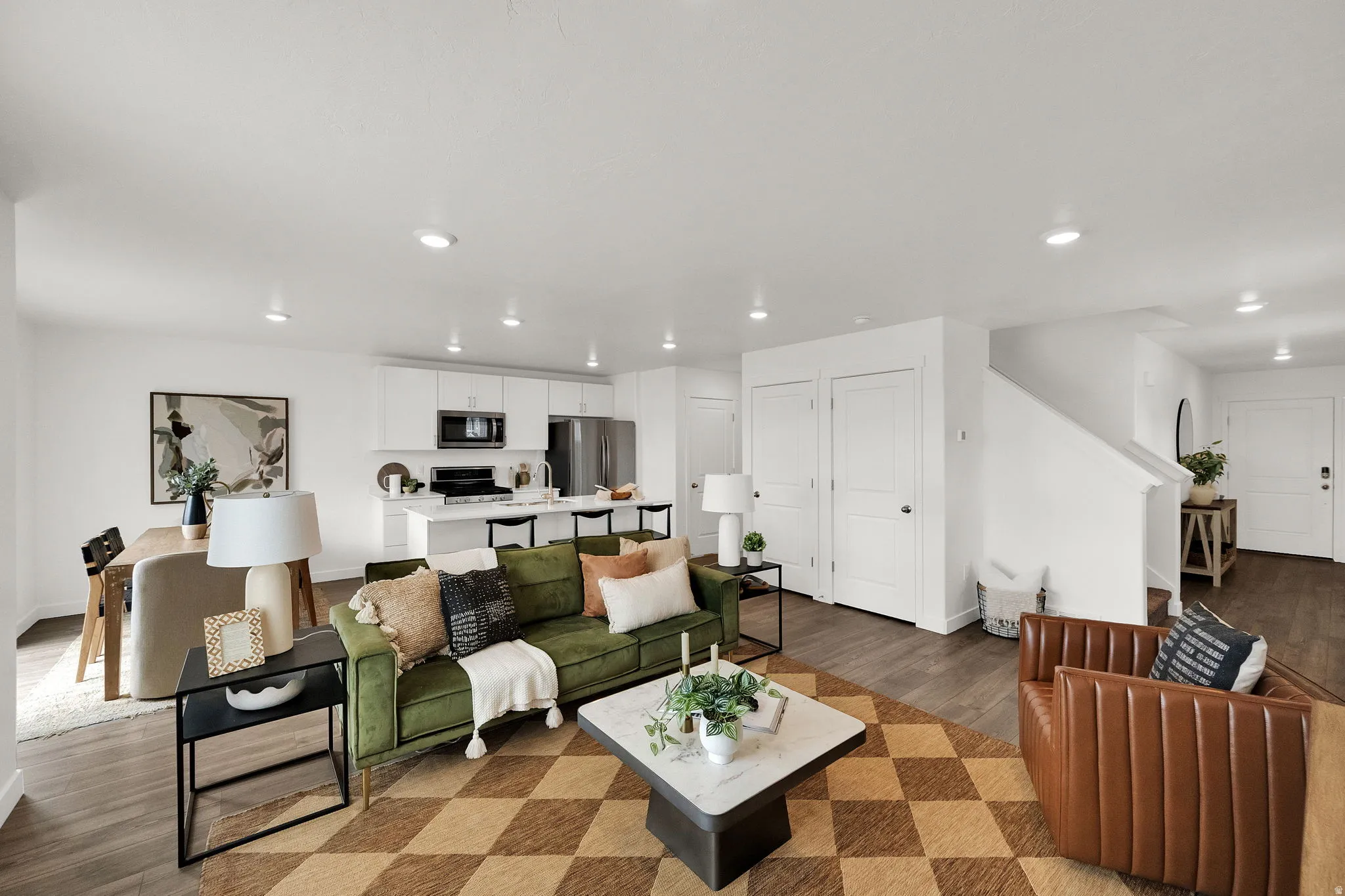 Open-concept living space featuring wood-finish flooring, recessed lighting, and a kitchen with white cabinetry