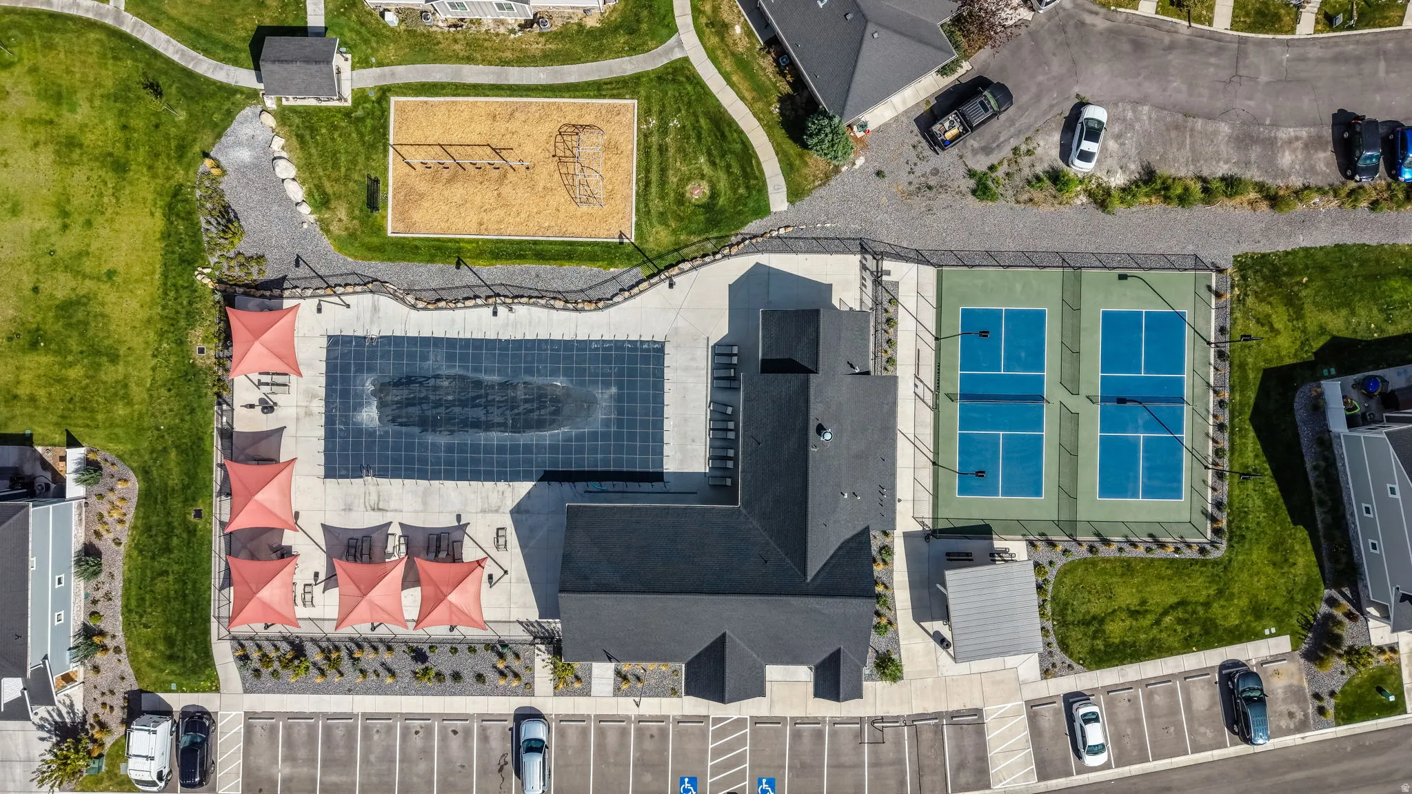 Community amenities featuring a swimming pool, shaded lounge areas, two pickleball courts, a playground, and ample parking