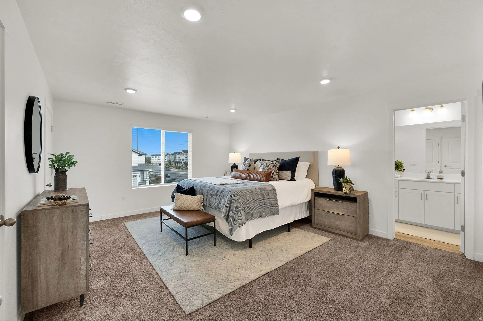 Recessed lighting illuminates a spacious room featuring a window with integrated blinds