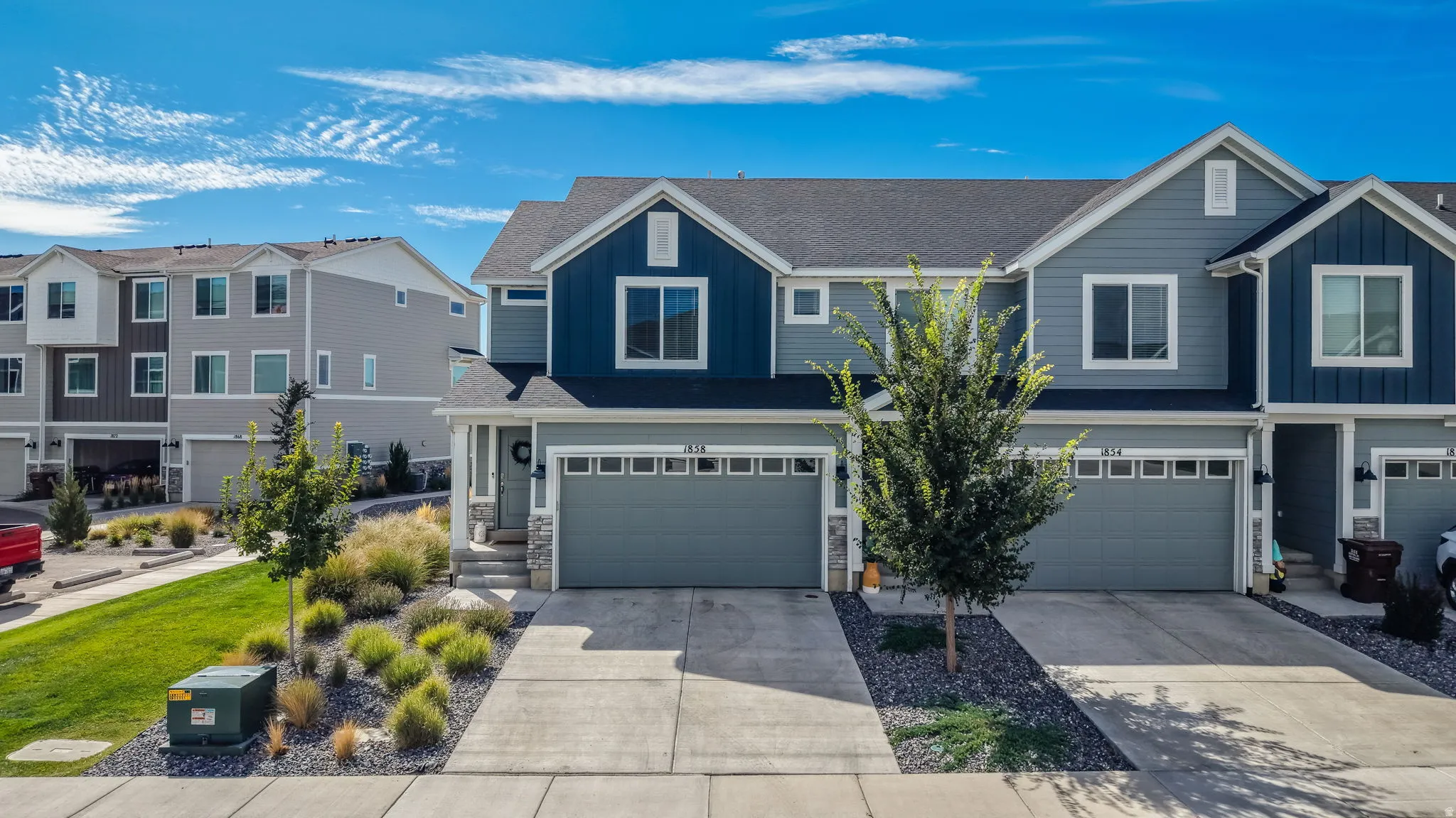 Contemporary multi-story exterior with a two-car garage, concrete driveway, and stone accents