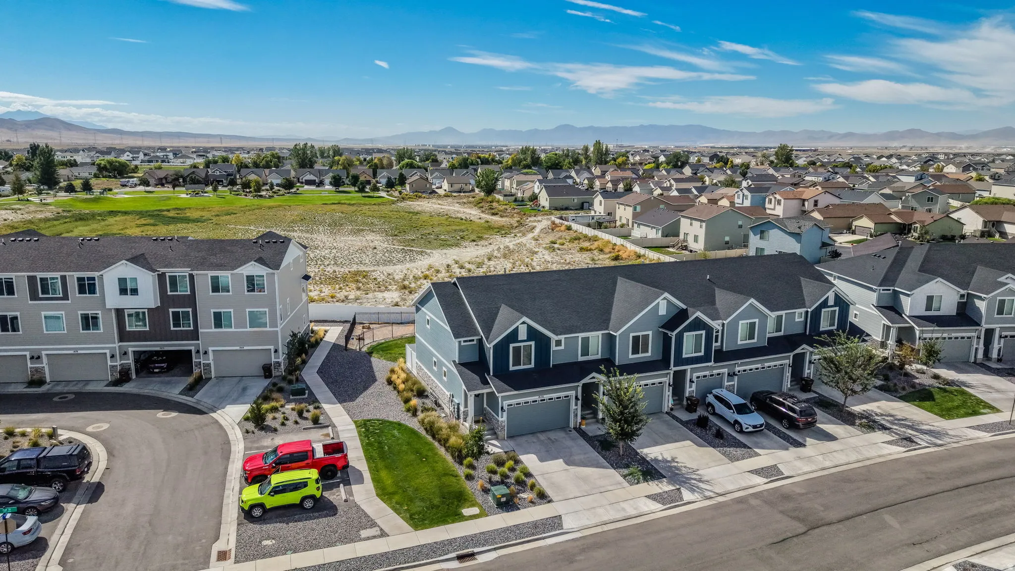 Townhome development featuring multi-story units, attached garages, and a paved driveway