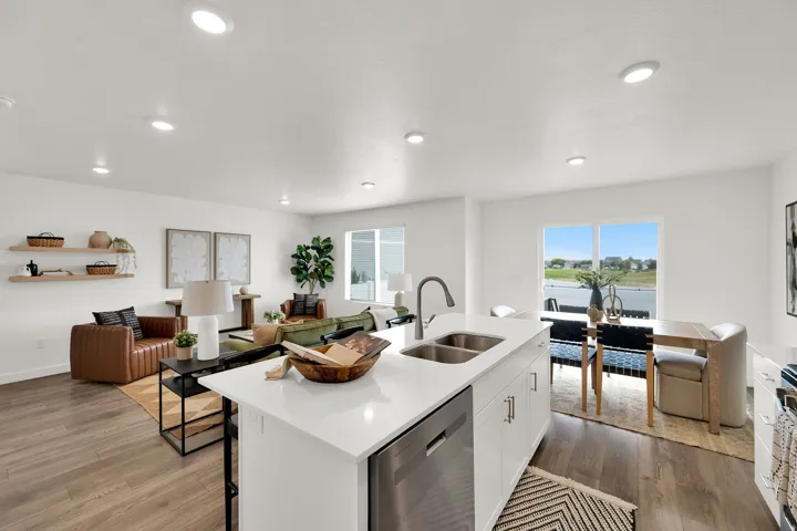 Open-concept living space featuring wood-finish flooring, recessed lighting, and a kitchen island with a stainless steel sink