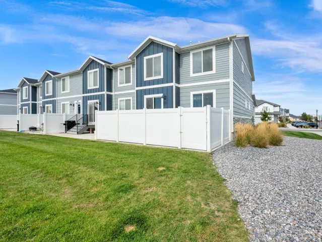 Exterior featuring multi-tone siding, white window trim, and a white privacy fence