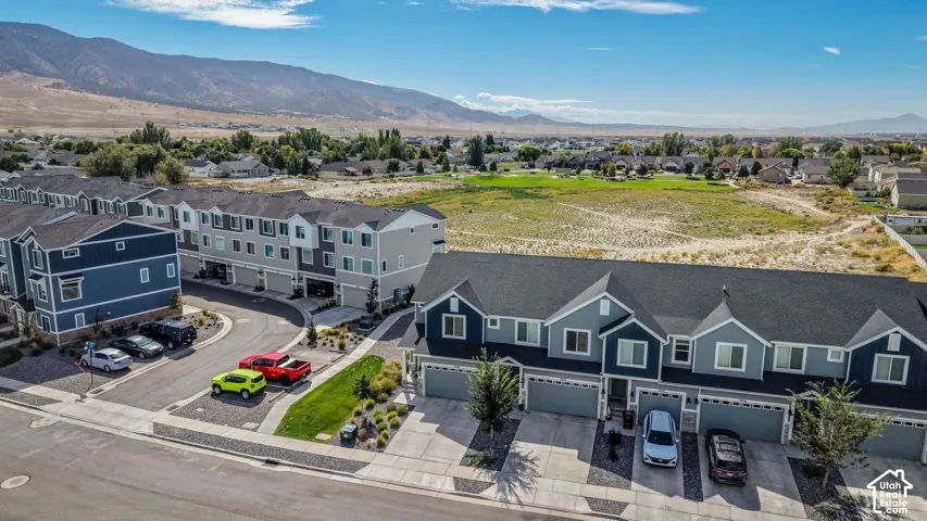 Townhome community with mountain scenery, attached garages, and paved driveways