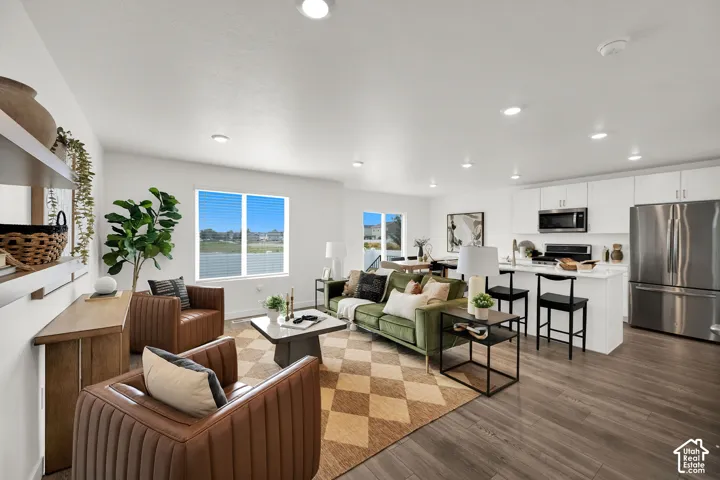 Open concept living area featuring wood-finish flooring, recessed lighting, and a kitchen island with seating