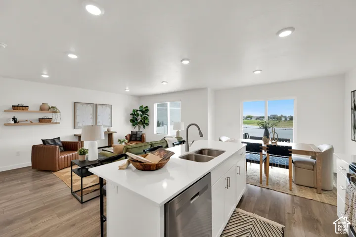 Open-concept living space featuring wood-finish flooring, recessed lighting, and a kitchen island with a stainless steel sink