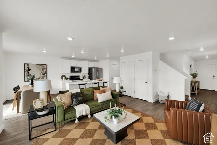 Open-concept living space featuring wood-finish flooring, recessed lighting, and a kitchen with white cabinetry