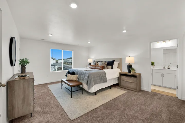 Recessed lighting illuminates a spacious room featuring a window with integrated blinds