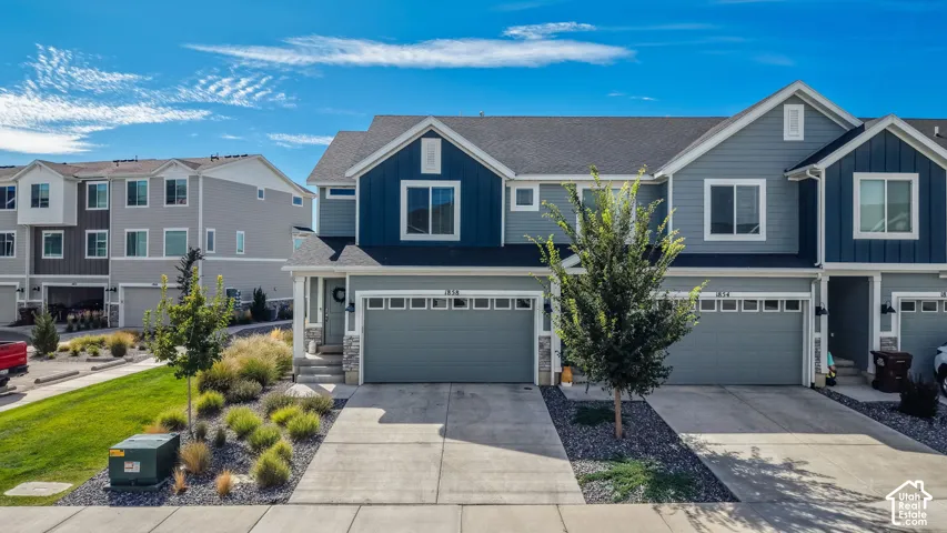 Contemporary multi-story exterior with a two-car garage, concrete driveway, and stone accents