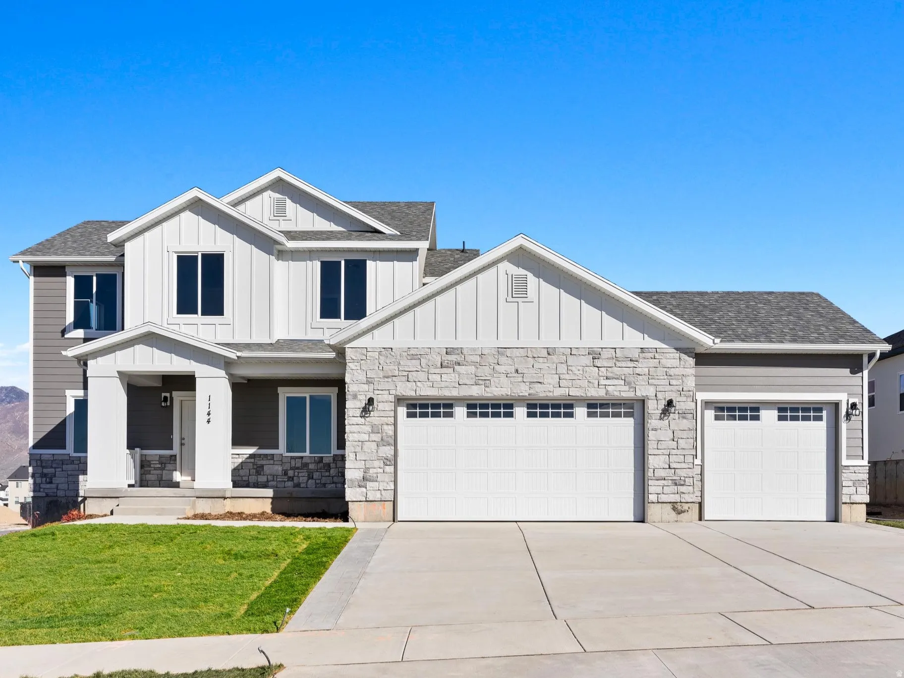 Contemporary exterior with stone accents, board and batten siding, multiple gables, and a two-car garage